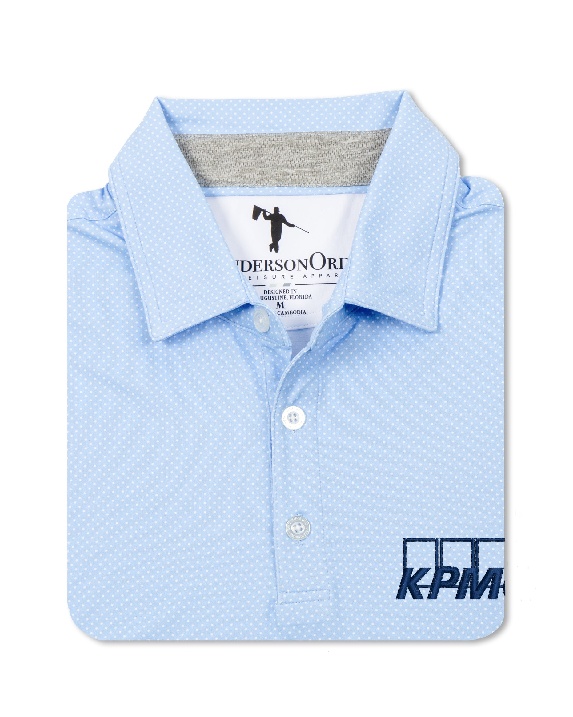 A light blue polo shirt with a subtle micro-dot pattern, folded neatly to show the collar, button placket, and a dark blue KPM logo printed on the lower right front.