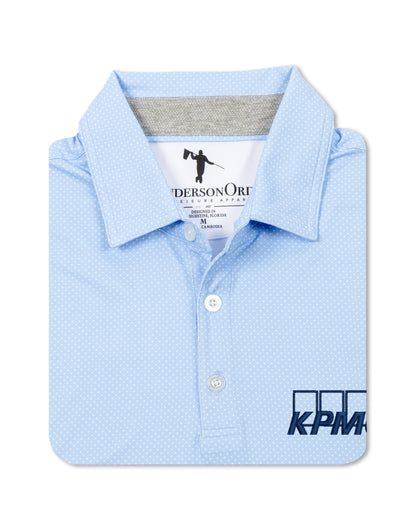 A light blue polo shirt with a subtle micro-dot pattern, folded neatly to show the collar, button placket, and a dark blue KPM logo printed on the lower right front.