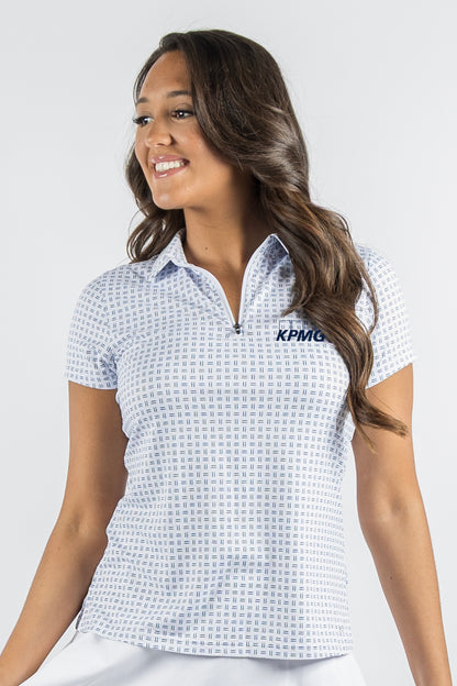 A woman wearing a white short-sleeve polo shirt with a light blue geometric grid pattern and a navy KPMG logo on the chest, photographed against a light gray studio background.