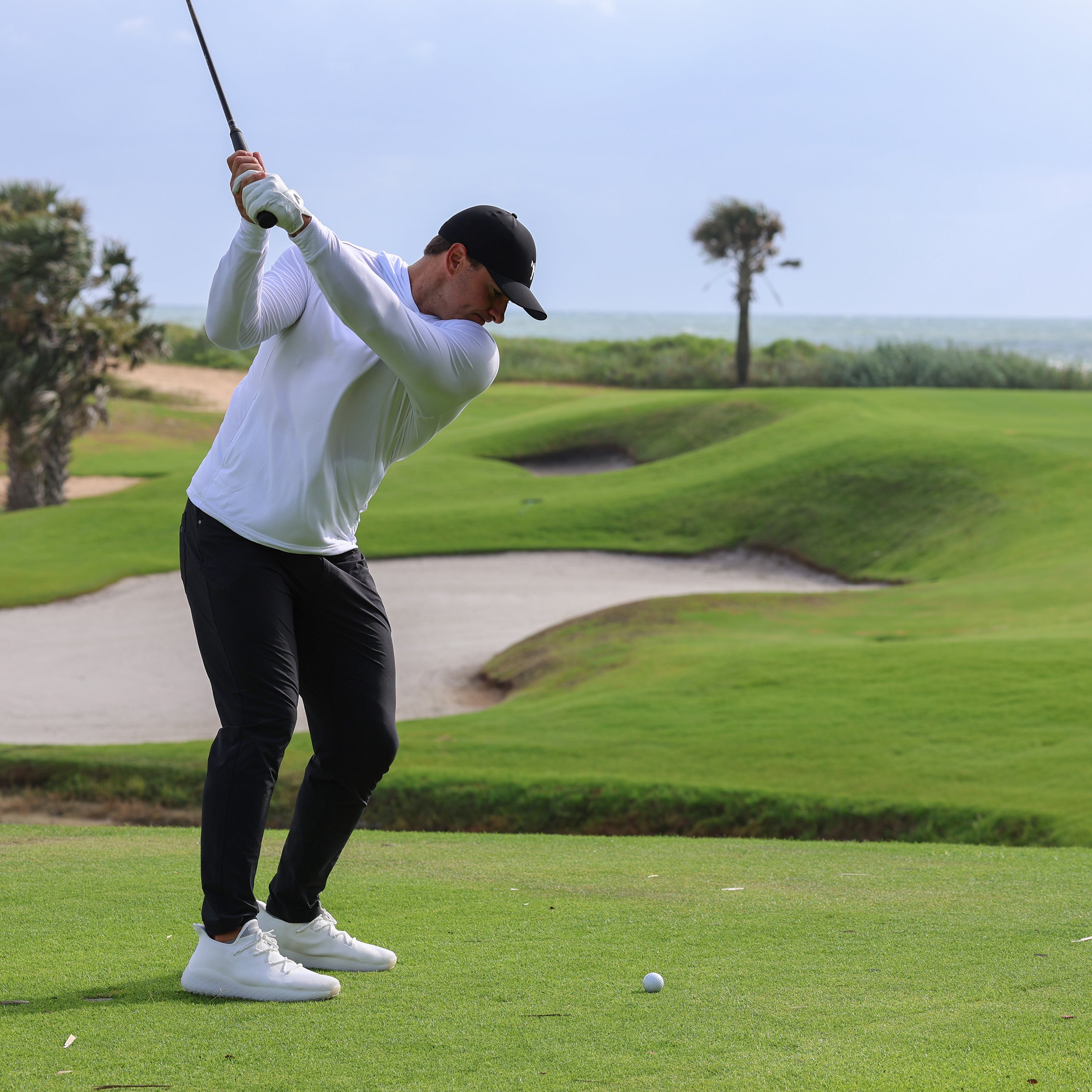 Man working on his swing wearing White casual golf shoes. the perfect shoes for running, golfing, pickleball or anything. The AO WAVE1, the Ultimate Crossover Performance Shoe.